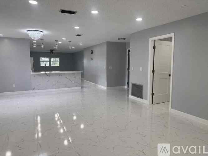 A spacious room with a marble floor and a door on the right side.