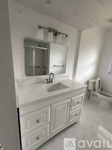 A bathroom with a sink, mirror, and toilet.
