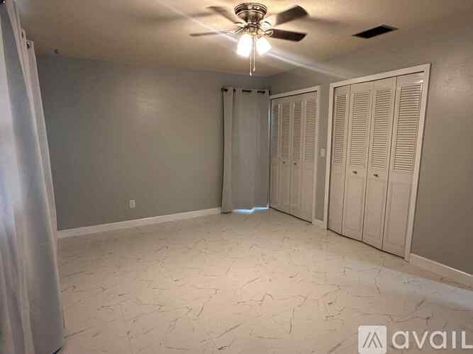 A room with a ceiling fan and a row of closets.