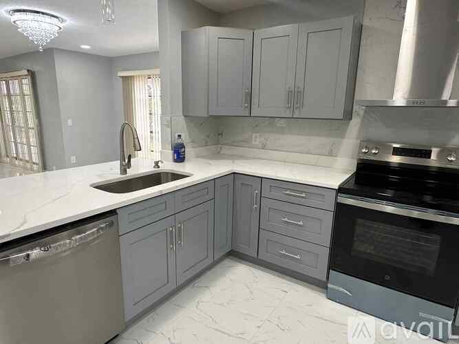 A kitchen with a white marble countertop and grey cabinets.