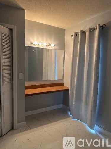 A bathroom with a mirror, lights, and a bench.