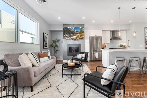 A modern living room with a grey couch, a black chair, and a fireplace.