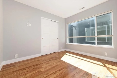 A room with a white door and a window with a view of a building outside.