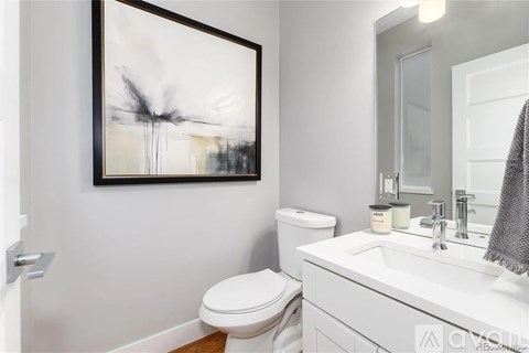 A white bathroom with a toilet, sink, and a painting on the wall.
