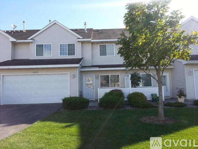 A house with a white garage door and a tree in front.