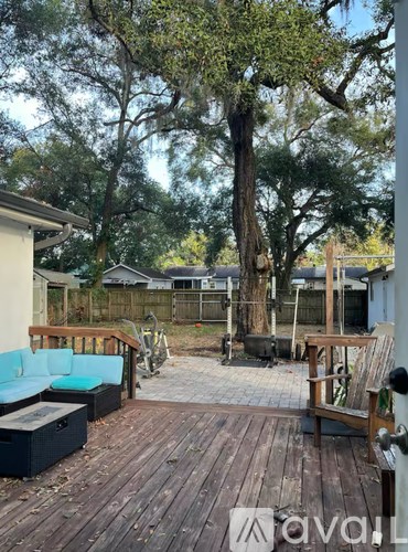 A wooden deck with a blue couch and a table surrounded by trees.