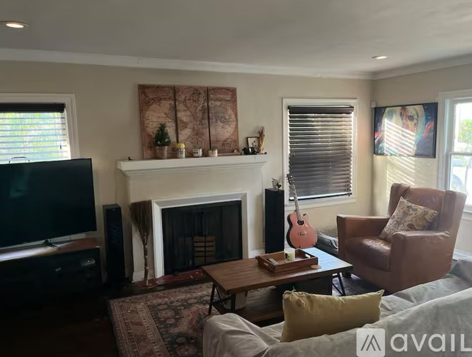 A living room with a fireplace, a television, and a guitar.