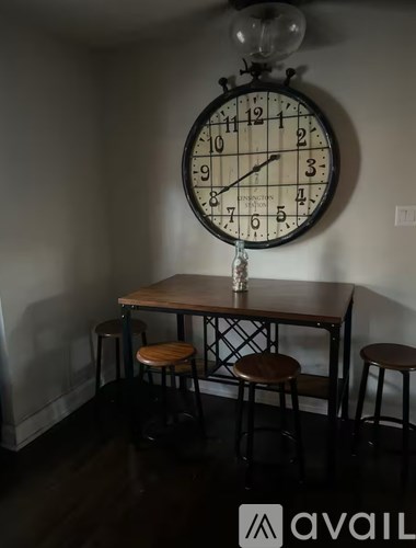A wall clock hangs above a table with stools.
