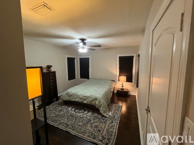 A bedroom with a bed, a rug, a lamp and a ceiling fan.