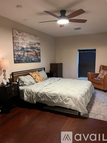 A bedroom with a bed, a chair, and a painting on the wall.