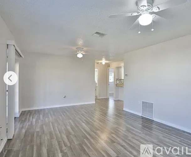 A spacious room with wooden flooring and a ceiling fan.