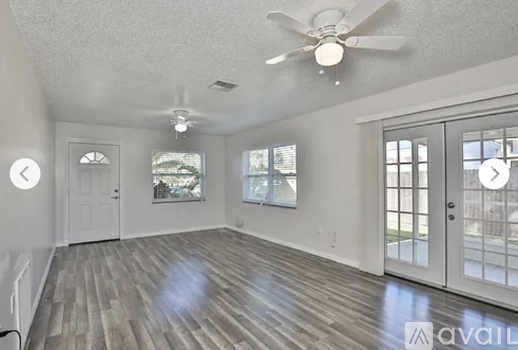 A spacious room with a ceiling fan and wooden flooring.