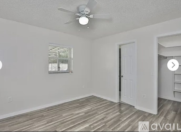A room with a ceiling fan and wooden flooring.