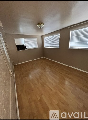 A room with wooden flooring and a window with blinds.