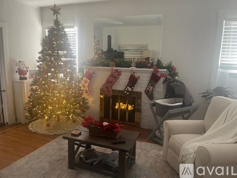 A living room decorated for Christmas with a lit tree and stockings.
