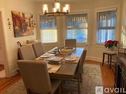 A dining room with a table set for six and a chandelier hanging from the ceiling.