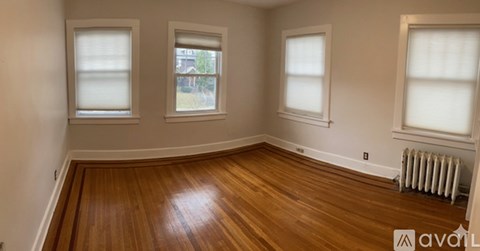 A room with wooden floors and three windows.