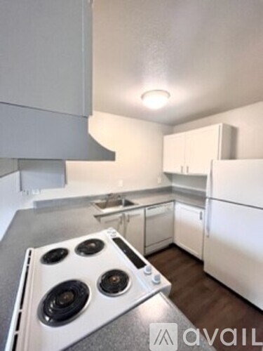 A kitchen with a stove top oven and white cabinets.