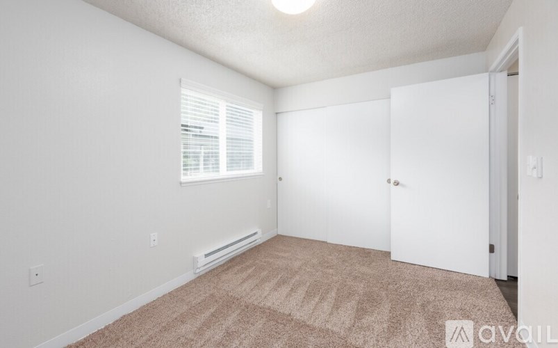 A room with a carpeted floor and a window with blinds.