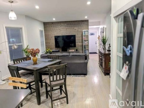 A modern living room with a brick fireplace and a dining area with a table and chairs.