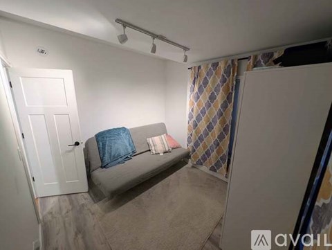 A small room with a grey couch and a checkered curtain.