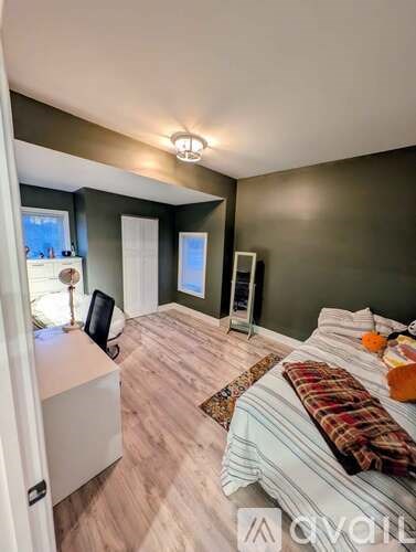 A bedroom with a bed, a chair, and a window.