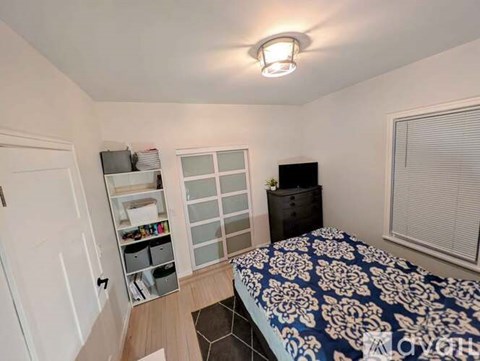 A bedroom with a bed, dresser, and window.