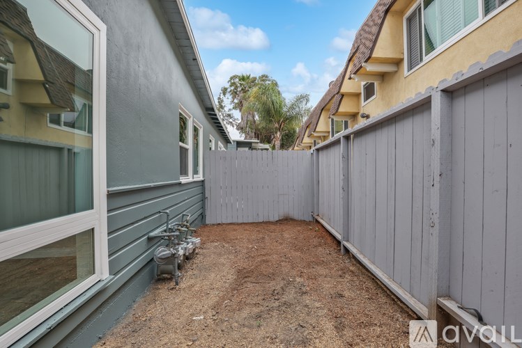 A backyard with a grey fence and a dirt ground.