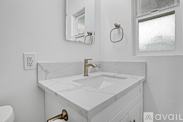 A white bathroom with a marble sink and a mirror above it.