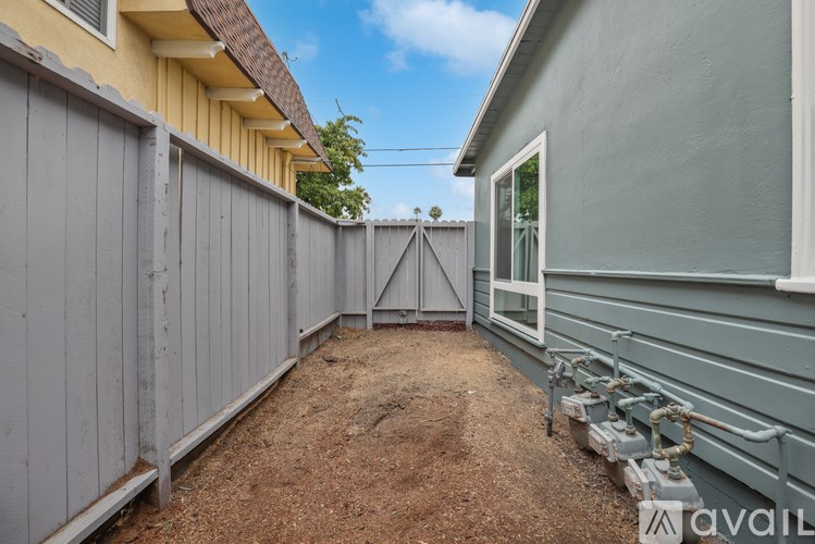 A backyard with a wooden fence and a grey wall.