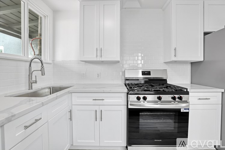 A modern kitchen with white cabinets and a stove top oven.