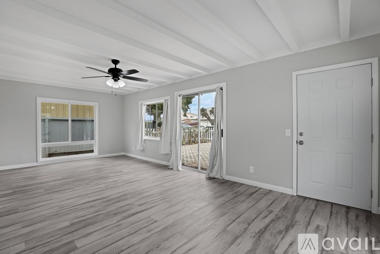A spacious room with a ceiling fan and wooden flooring.