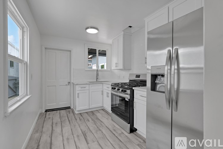 A modern kitchen with a stainless steel refrigerator, oven, and wooden flooring.