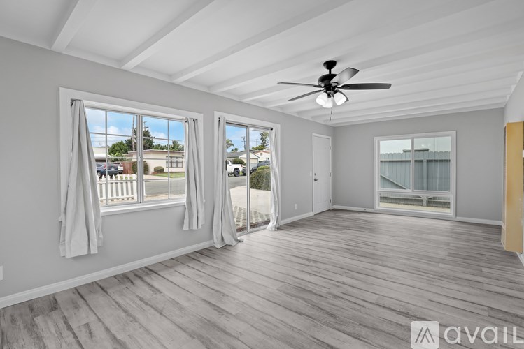 A spacious room with a ceiling fan and sliding glass doors leading to a balcony.