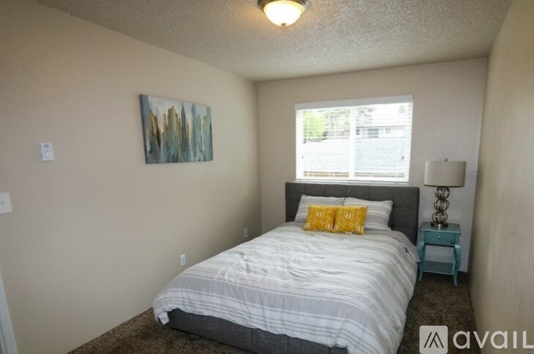 A bedroom with a bed, nightstand, and a painting on the wall.