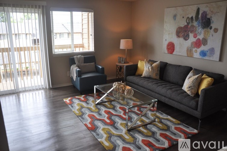 A living room with a black couch, a blue chair, and a colorful rug.