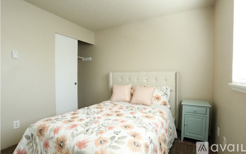A bedroom with a floral bedspread and a white headboard.