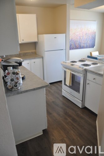 A kitchen with white appliances and wooden floors.