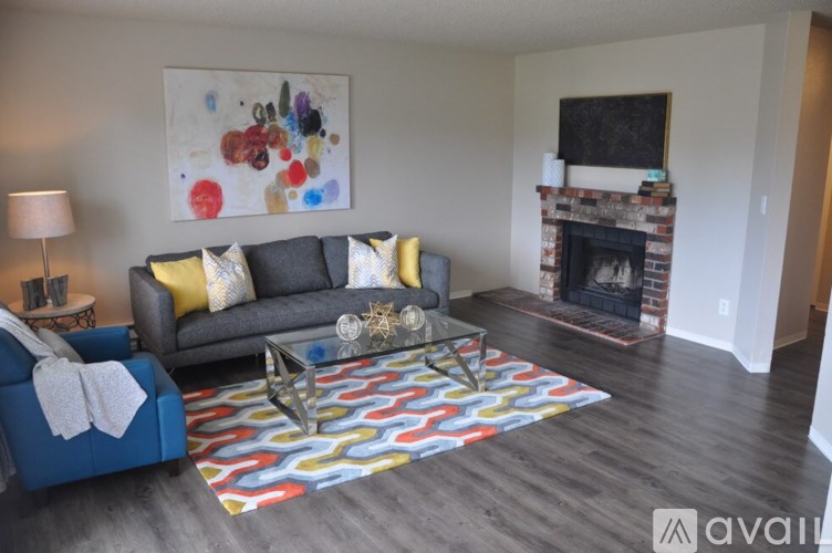 A living room with a grey couch, a blue chair, a coffee table, and a fireplace.