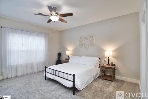A bedroom with a bed, a ceiling fan, and two lamps.