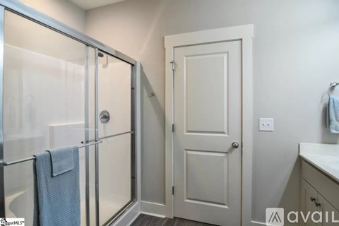A bathroom with a glass shower door and a white door.