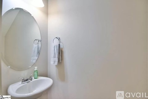 A white sink with a green soap and a mirror above it.
