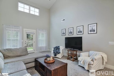 A living room with a grey couch, a wooden coffee table, and a television.