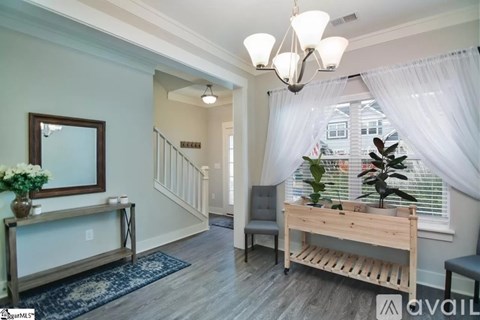 A well-lit hallway with a bench, chair, and a plant.