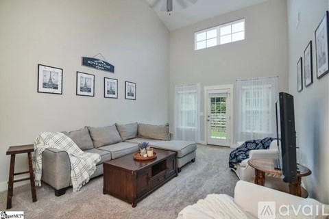 A living room with a grey couch, a coffee table, and a television.