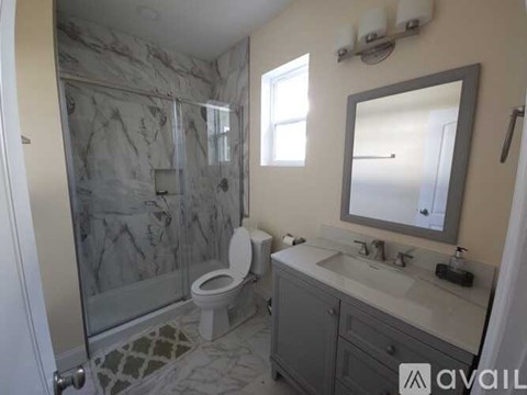 A bathroom with a marble shower and a toilet.