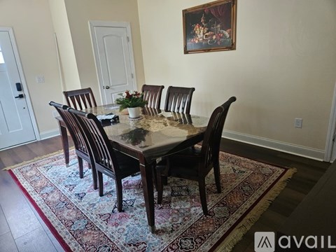 A dining table with chairs and a painting on the wall.