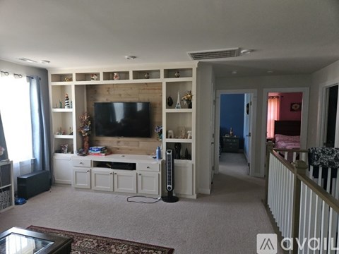 A living room with a flat screen TV and a white entertainment center.