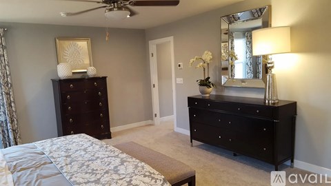 A bedroom with a bed, dresser, mirror, and a ceiling fan.
