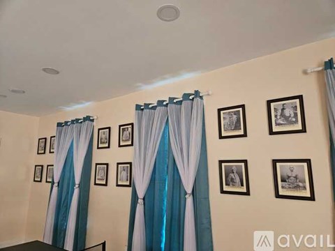 A room with a white ceiling and a wall with pictures and curtains.